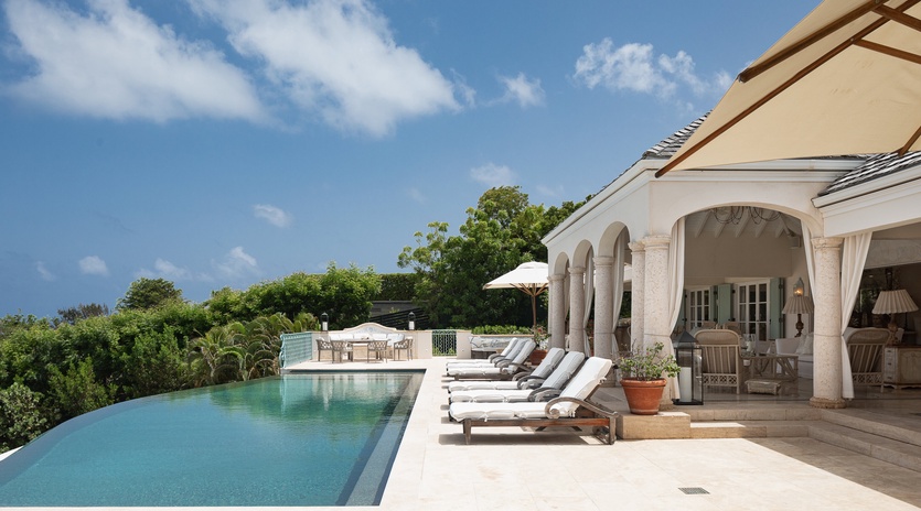 Stretch out on plush loungers beside your private infinity pool, where elegant arches frame tropical vistas and the sparkling water blends seamlessly with the horizon.