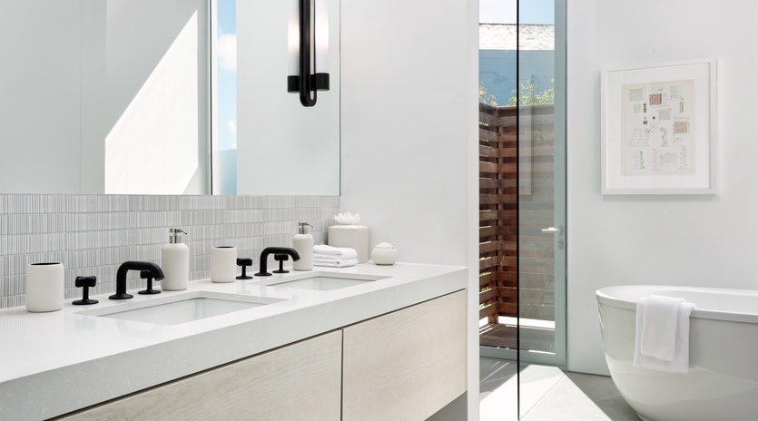 Soak in your luxurious spa-like bathroom featuring a sleek soaking tub, modern dual vanity, and stunning natural light flooding through floor-to-ceiling windows.