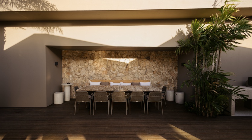 Gather around your private outdoor dining table, where natural stone walls and tropical palms create the perfect setting for memorable meals together.