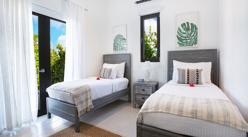 You'll rest peacefully in this bright twin bedroom with crisp linens, tropical art, and natural light streaming through the windows. The air conditioning keeps you comfortable all day.