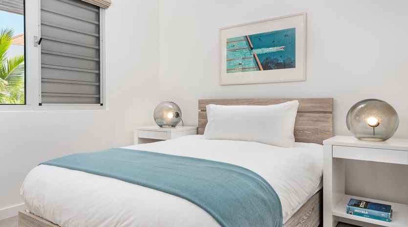 Rest peacefully in your comfortable bedroom with coastal artwork and modern lighting creating a serene atmosphere.