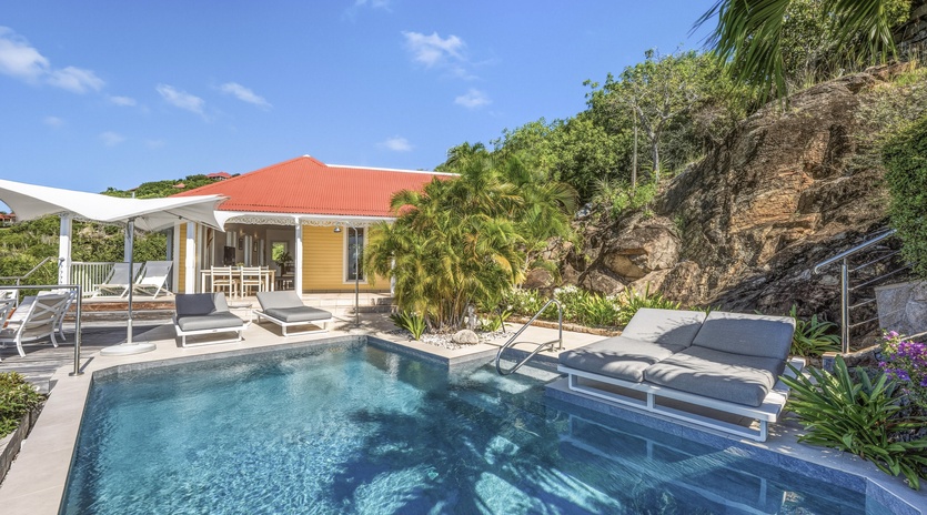 Soak up tropical sunshine beside your private pool, surrounded by lush palms and dramatic hillside views in this serene Caribbean-style retreat.