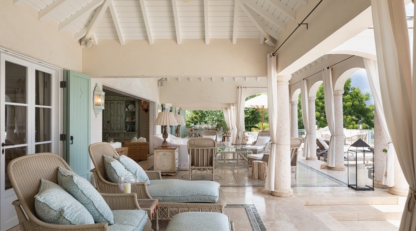 Settle into plush seating beneath soaring white beams and flowing curtains, where soft sea breezes and garden views invite you to unwind in elegant comfort.