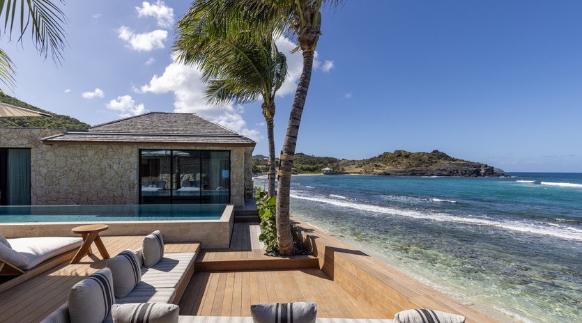 Beachfront villa with infinity pool, palm trees, and pristine ocean waters just steps from the shore.