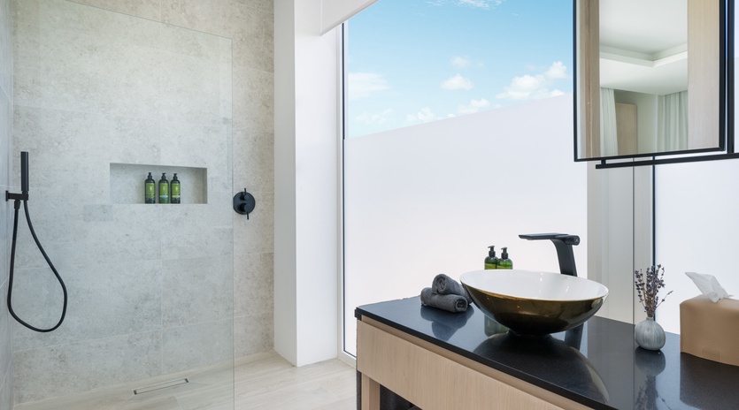 Step into your private spa-like bathroom with a sleek rain shower, modern vessel sink, and soft luxury towels waiting for you after a refreshing rinse.