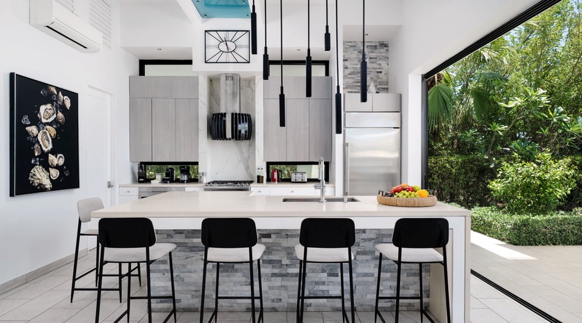 Picture yourself cooking in this stunning modern kitchen with a sleek marble island, pendant lighting, and refreshing garden views through floor-to-ceiling glass doors.