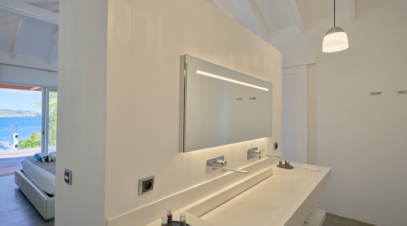 Enjoy your morning routine in this sleek bathroom with stunning sea views through the window.