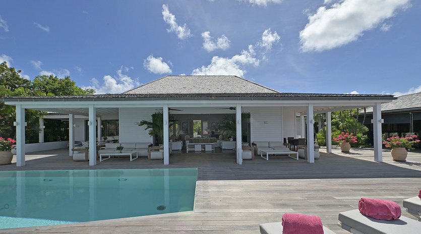 Modern villa with open-air design featuring pristine pool, spacious covered terraces, and tropical gardens under Caribbean skies.