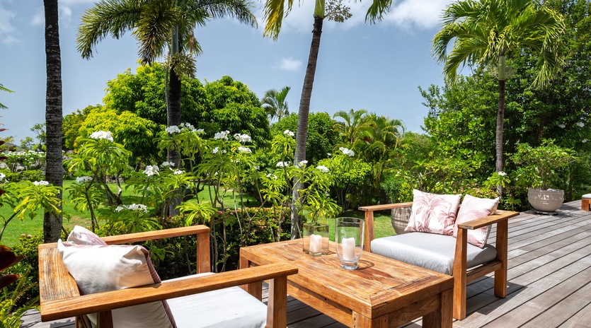 Relax on your private tropical deck with plush seating surrounded by swaying palms and lush greenery—your perfect paradise retreat.
