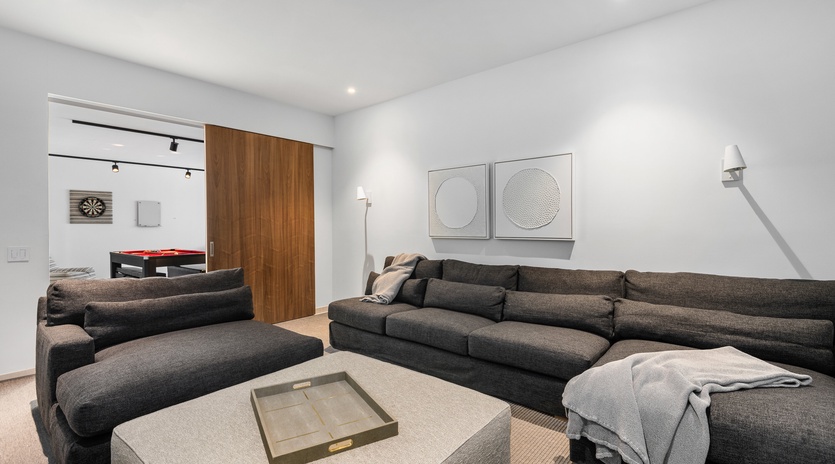 Sink into plush sectional seating while your game room beckons beyond sleek sliding doors—perfect for unwinding after adventures.