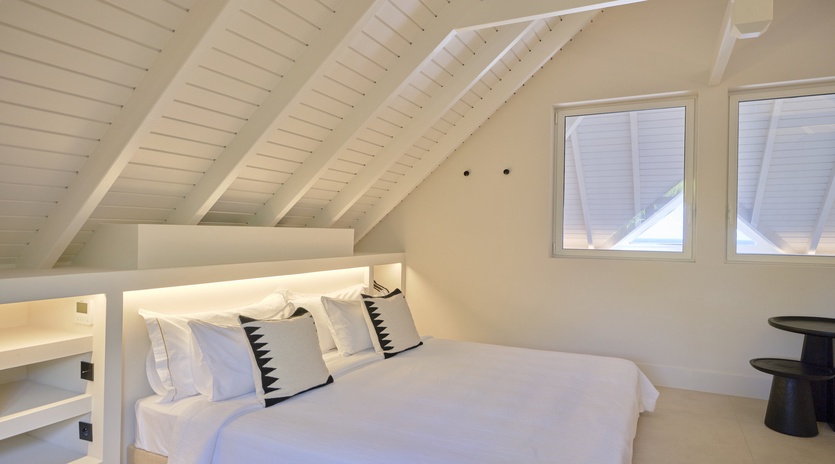 Your peaceful attic bedroom awaits with crisp white linens, exposed beams, and cozy sloped ceilings that create an intimate retreat.
