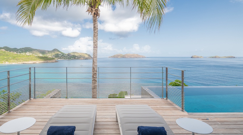 Unwind on your private deck with stunning ocean views, loungers, and tropical palm shade—pure Caribbean paradise awaits.