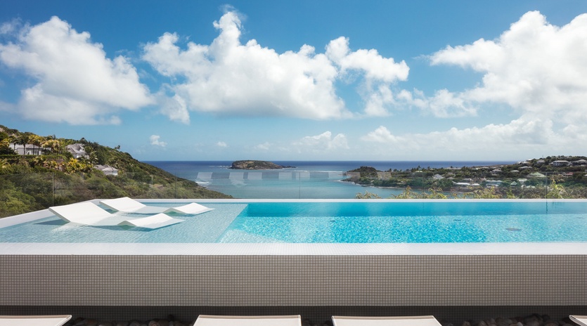 Infinity pool seamlessly blends with turquoise Caribbean waters and dramatic coastline views.