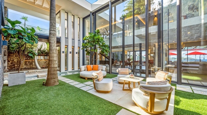 Step into your private courtyard sanctuary where modern luxury meets tropical tranquility, featuring plush seating surrounded by lush palms and open-air elegance.
