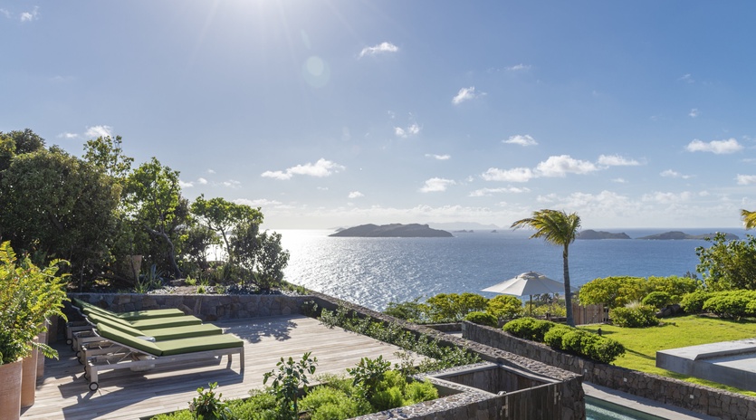 Stunning oceanfront terrace featuring pristine pool, tropical gardens, and breathtaking island views across sparkling Caribbean waters.