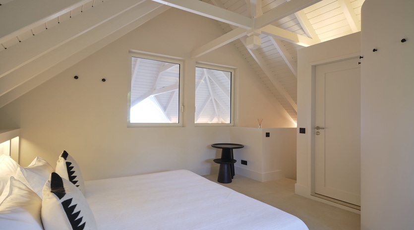 Your bright attic bedroom features crisp white bedding and charming exposed beams, creating a peaceful retreat under the sloped ceiling.