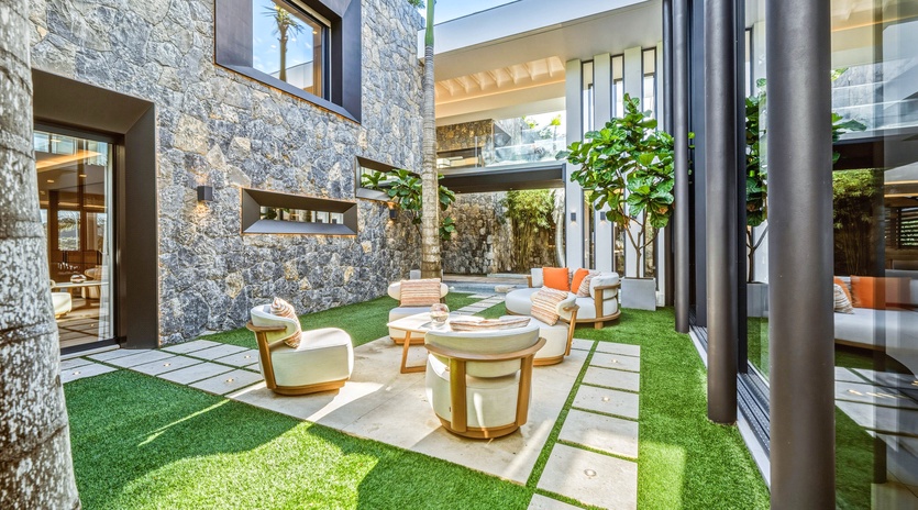 Your private courtyard oasis features modern seating surrounded by lush greenery and striking stone walls.