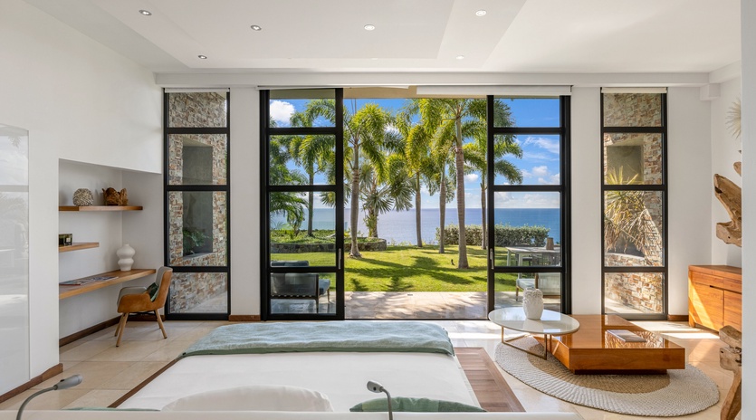 Sink into this stunning oceanfront living space where floor-to-ceiling windows frame palm trees and endless sea views.