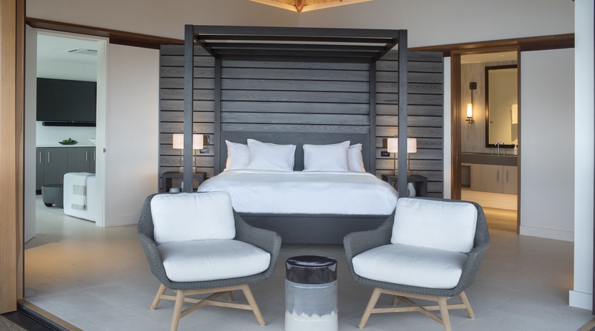 Retreat to your elegant suite with modern four-poster bed, cozy seating area, and soaring bamboo ceiling that creates a serene tropical sanctuary.