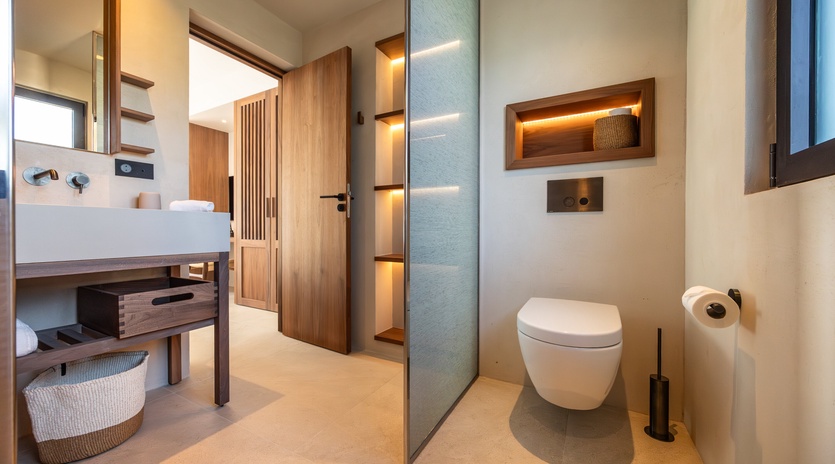 Your private bathroom features sleek modern design with warm wood accents, ambient lighting, and thoughtful touches for a spa-like experience.