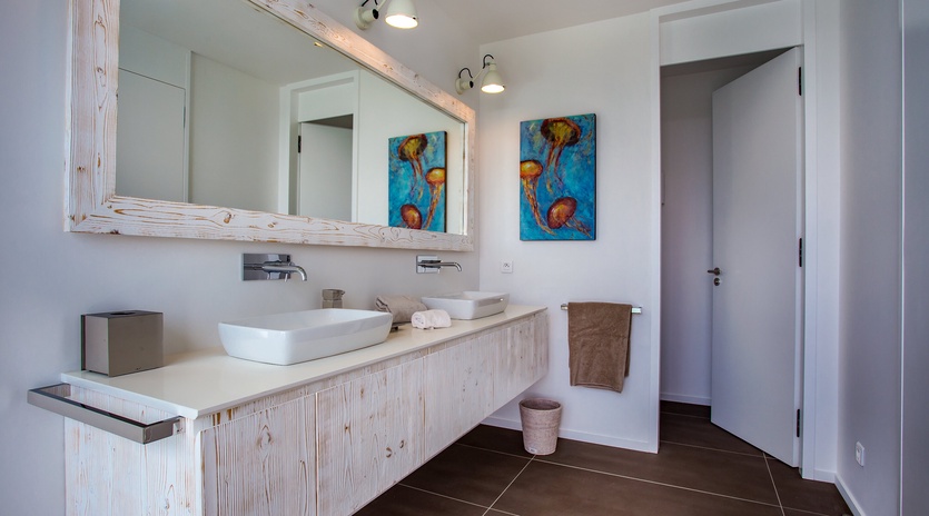 Refresh in your stylish bathroom featuring natural wood vanity, modern fixtures, and colorful jellyfish artwork that brings the ocean indoors.