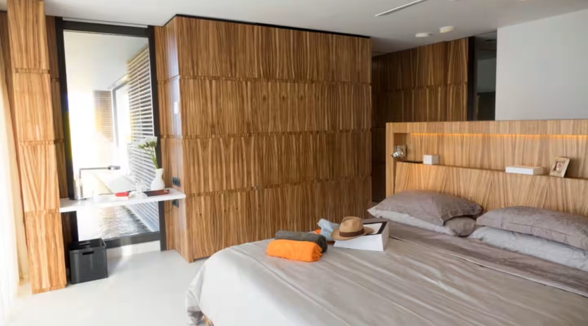 Step into your stylish retreat with warm wood paneling, a ceiling fan for comfort, and a peaceful view of your private outdoor space—your restful escape awaits.