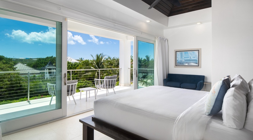 Wake up to tropical paradise views from your spacious bedroom featuring crisp linens, modern comfort, and direct balcony access to enjoy morning coffee.