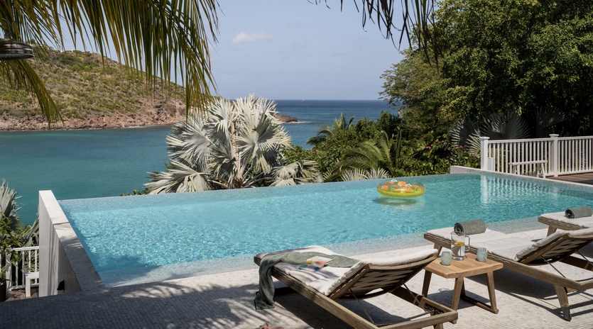 Unwind by your private infinity pool where crystal-clear waters blend seamlessly with stunning ocean views through swaying palms.