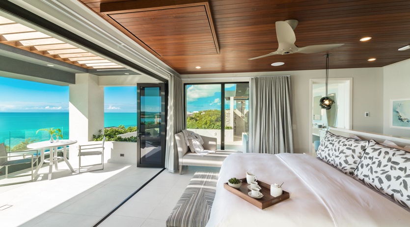Wake up to stunning turquoise waters framed by floor-to-ceiling glass doors that open to your private balcony. The warm wood ceiling and coastal-chic décor create a serene, luxurious retreat.