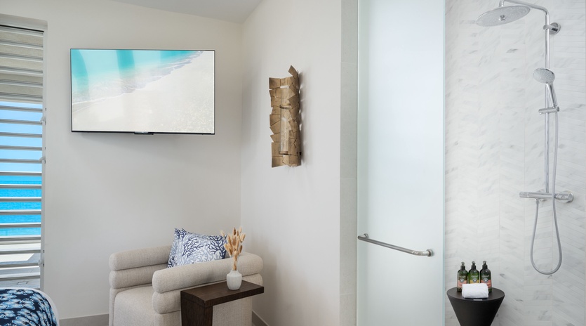 Your spacious suite features a luxurious walk-in shower with rainfall head and premium amenities, plus a cozy seating nook for ultimate relaxation.