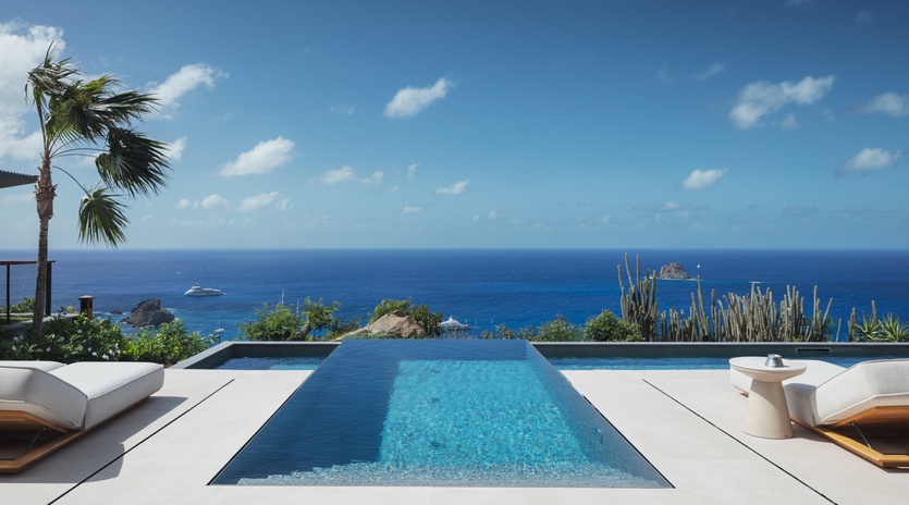 Stunning infinity pool overlooking endless ocean views with tropical landscaping and comfortable lounging areas.