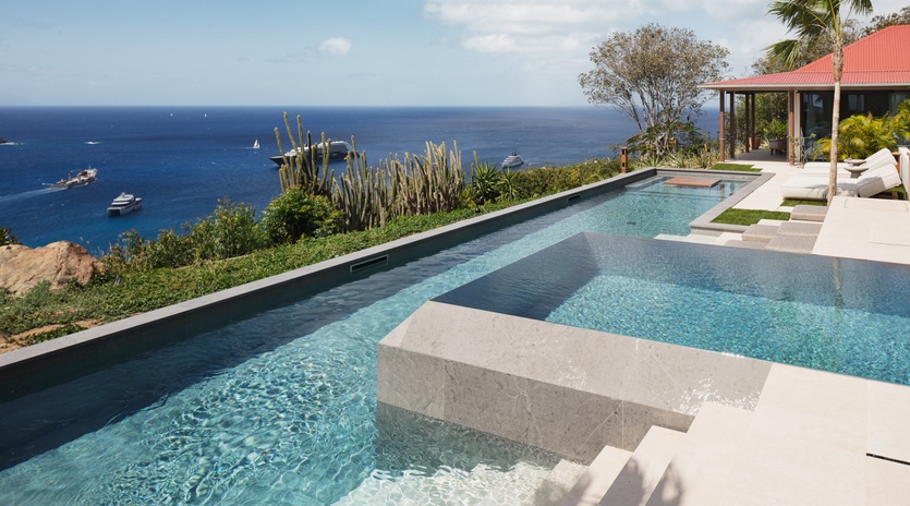 Stunning infinity pool overlooking the azure Caribbean sea, with luxury villa and tropical gardens creating the perfect island escape.