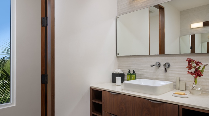 Step into your private spa-like bathroom featuring sleek modern fixtures, warm wood vanity, and tropical garden glimpses through the window.