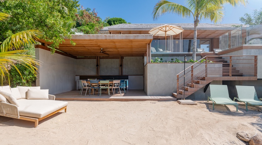 Modern beachfront villa featuring contemporary architecture surrounded by tropical palms and lush landscaping.