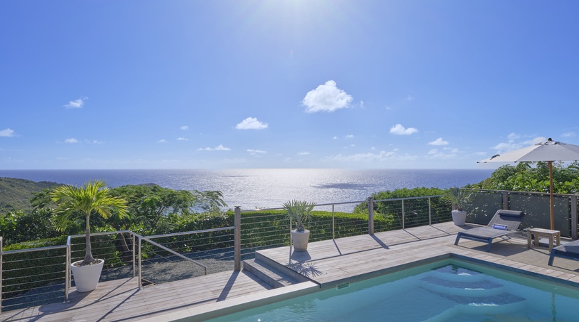 Private pool deck with stunning ocean views under brilliant blue skies and warm sunshine.