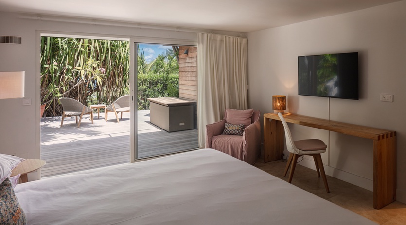 Step into your serene bedroom retreat where sunlight filters through sliding doors, revealing your private terrace with lush garden views. A cozy armchair beckons, and modern touches keep you comfortable.