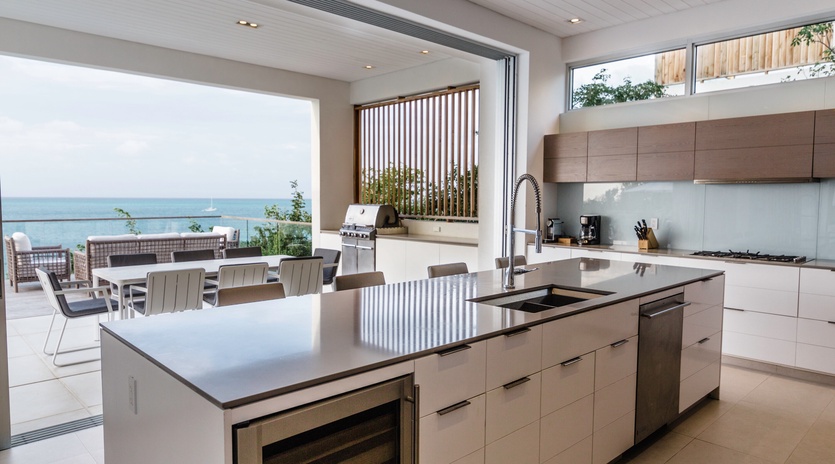 Cook with stunning sea views in this modern kitchen with sleek island and outdoor dining space.