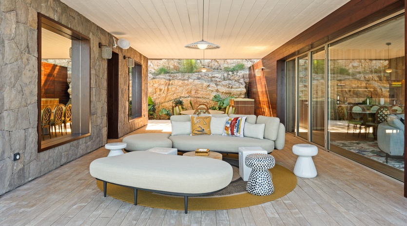 Sink into plush seating in your covered outdoor living space, where natural stone walls and modern comfort create the perfect retreat.