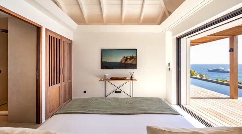 Step into your serene living space where warm wood meets stunning ocean views through floor-to-ceiling windows.