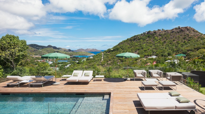Luxurious infinity pool deck with panoramic ocean and hillside views creates the perfect setting for your Caribbean retreat.