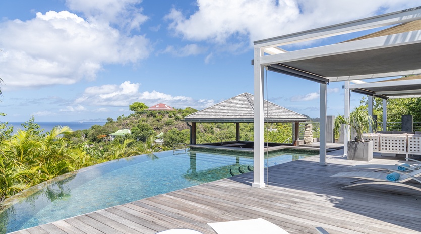 Immerse yourself in tropical luxury with a stunning infinity pool overlooking lush hills and the sparkling sea—your private oasis awaits.