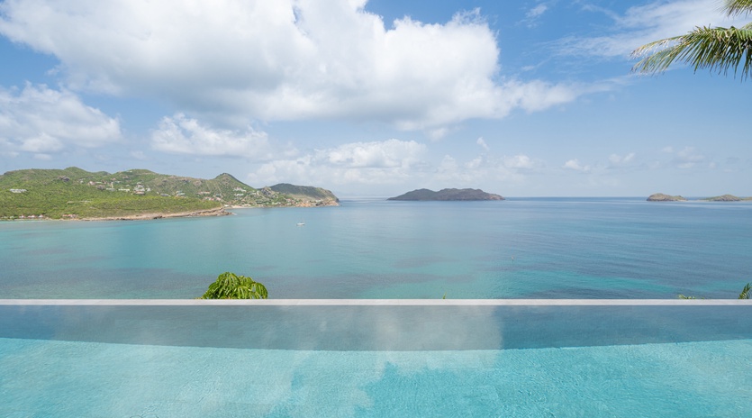 Infinity pool seamlessly blends with turquoise Caribbean waters and tropical islands beyond.
