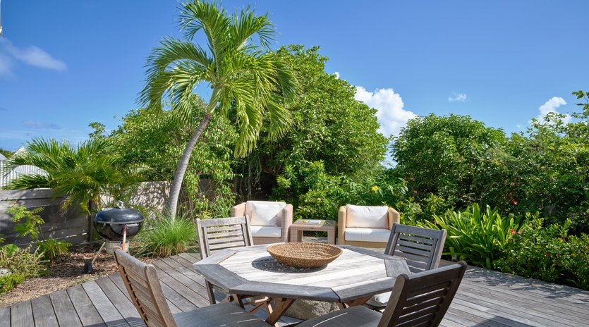 Relax on your private deck surrounded by tropical palms, where outdoor dining meets paradise under endless blue skies.