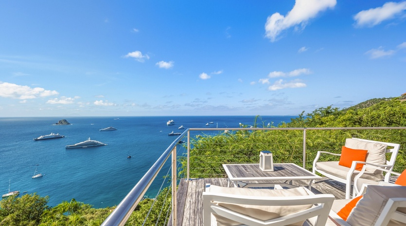 Stunning oceanfront terrace with panoramic sea views and luxury yachts dotting the azure waters below.