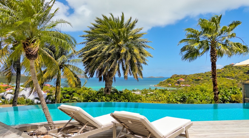 Stretch out on your private sun lounger beside the infinity pool, where turquoise waters blend seamlessly with ocean views and swaying palms frame your tropical escape.