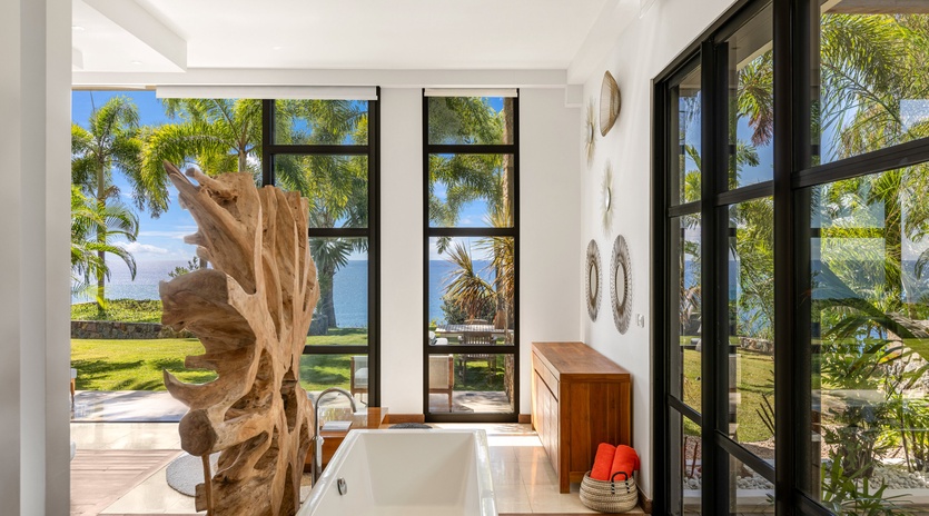 Soak in your private tub surrounded by floor-to-ceiling windows showcasing tropical palms and ocean views.