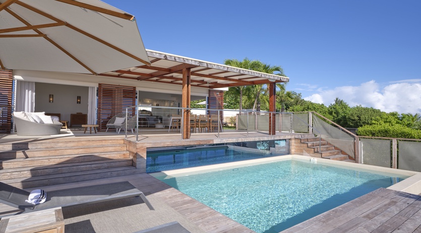 Stunning modern villa featuring a pristine swimming pool surrounded by elegant wooden decking and tropical greenery.