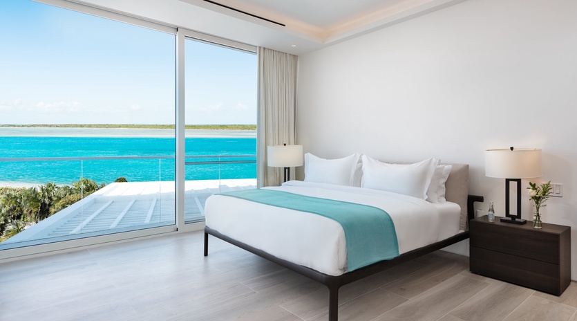Wake up to stunning turquoise waters just beyond your window. Your serene bedroom offers floor-to-ceiling views, plush white bedding, and a private balcony where you can soak in the coastal beauty.