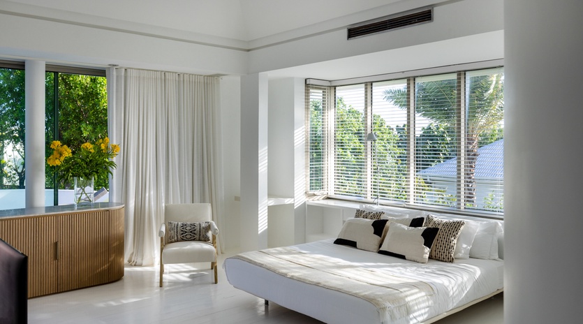 Unwind in your serene white bedroom with garden views, modern furnishings, and refreshing air conditioning for perfect comfort.