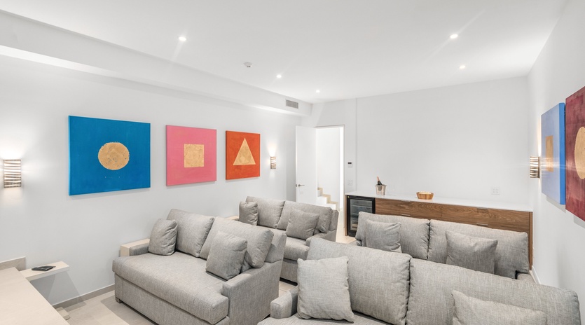 Sink into plush gray sofas surrounded by vibrant geometric art in your spacious, light-filled living area with soaring ceilings.